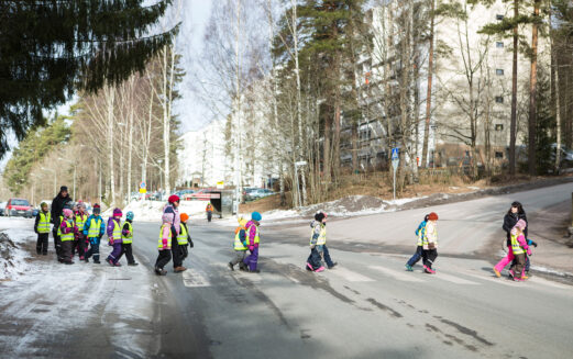 Päiväkotiryhmän lapsia ylittämässä suojatietä heijastinliivit päällään.